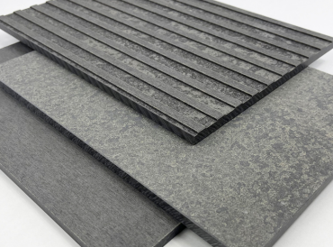 Drei übereinanderliegende Faserzementtafeln in verschiedenen dunkelgrauen Oberflächen: eine mit feiner Rillenstruktur, eine mit wolkiger Textur und eine glatt geschliffene – Darstellung der Materialvielfalt für vorgehängte hinterlüftete Fassaden.