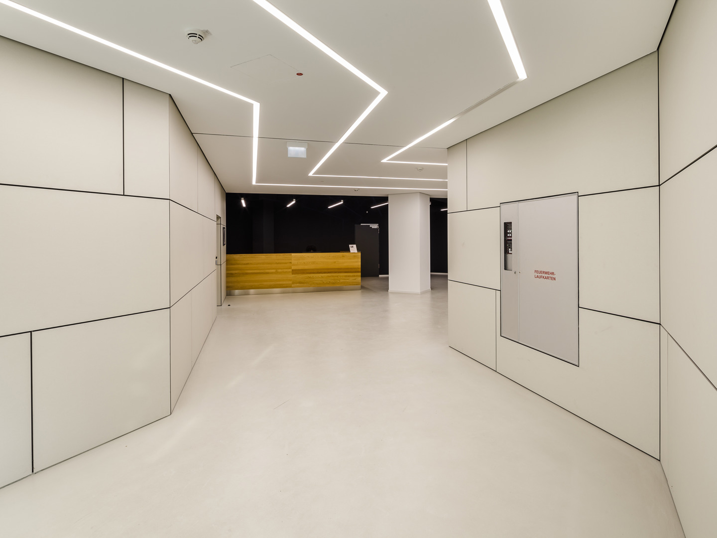 Moderner Innenraum mit präzise gefügten Faserzementtafeln an den Wänden – betont durch lineare LED-Beleuchtung in der Decke, entsteht ein puristisches, architektonisch anspruchsvolles Gestaltungskonzept mit klarer Geometrie und technischer Raffinesse.